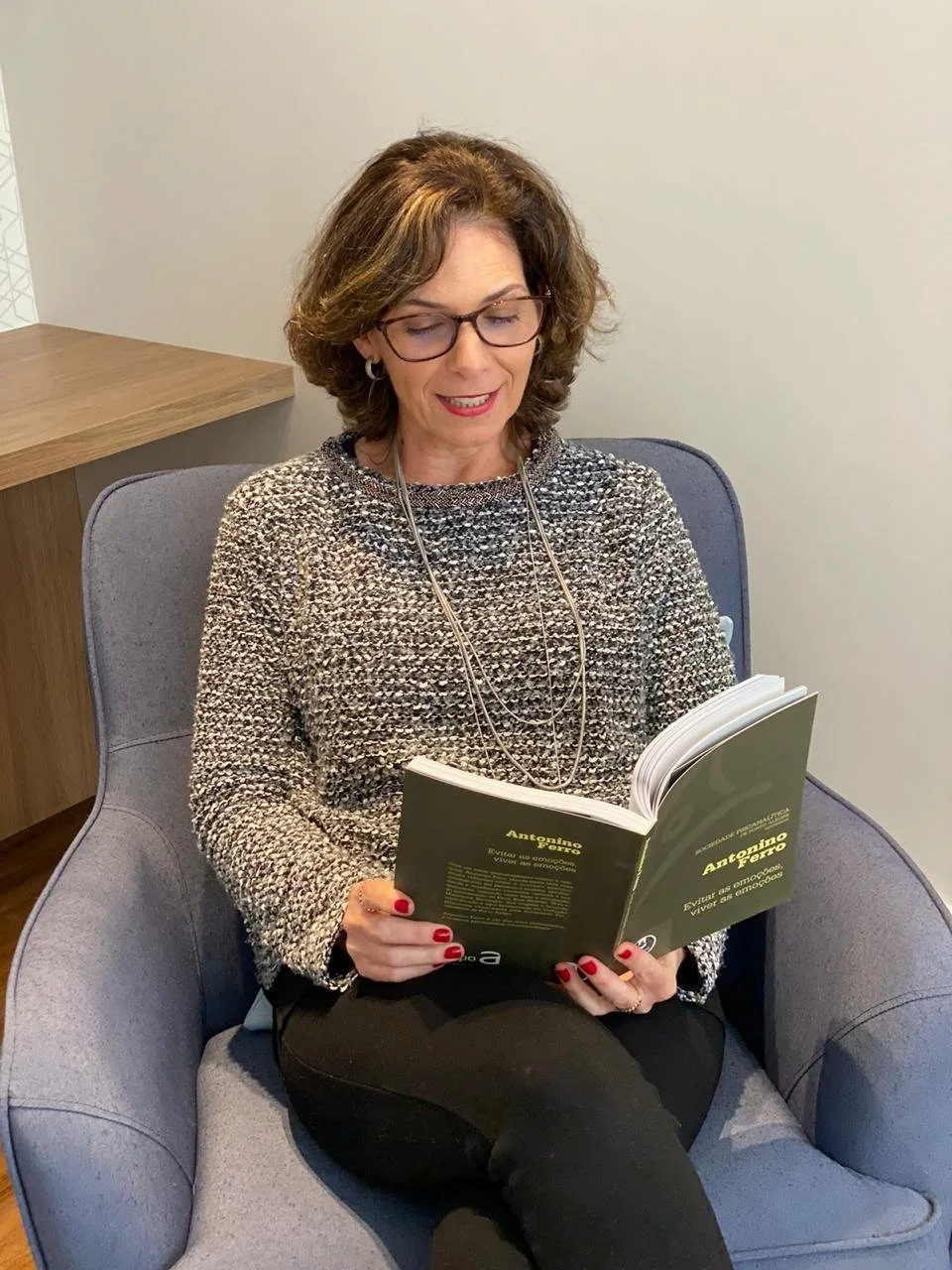 Gisela lendo na poltrona do consultório