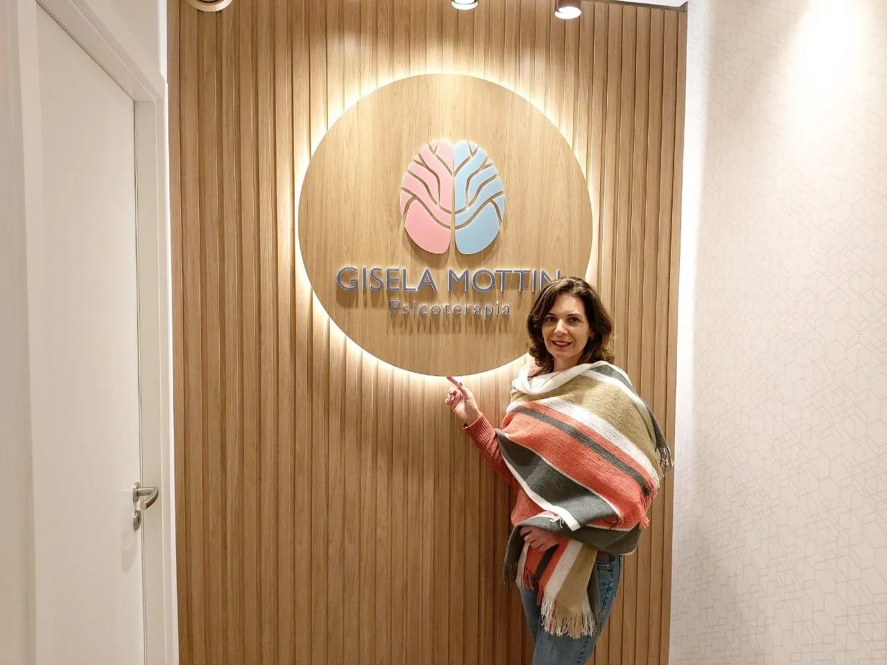 Gisela ao lado da logo do consultório