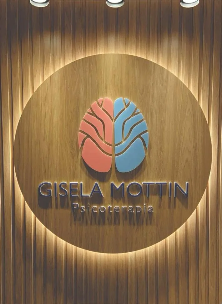 Logo Gisela Mottin Psicoterapia iluminada em painel de madeira