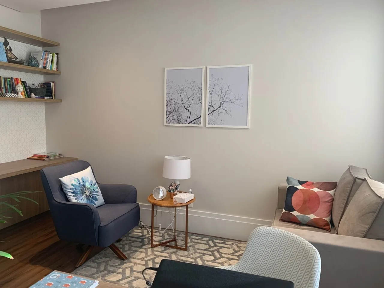 Sala de atendimento com poltrona, sofá e quadros de árvores